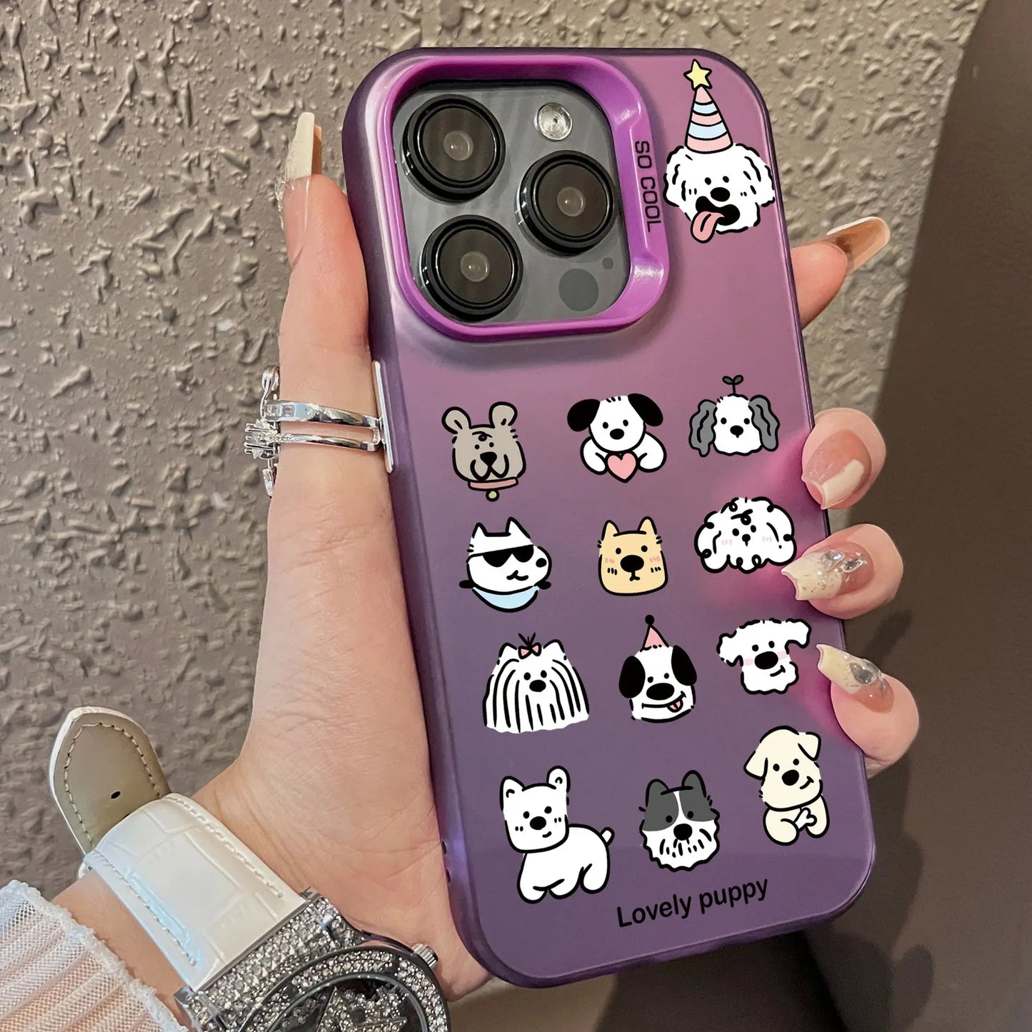 Hand holding a purple phone case with dog illustrations on a textured wall background