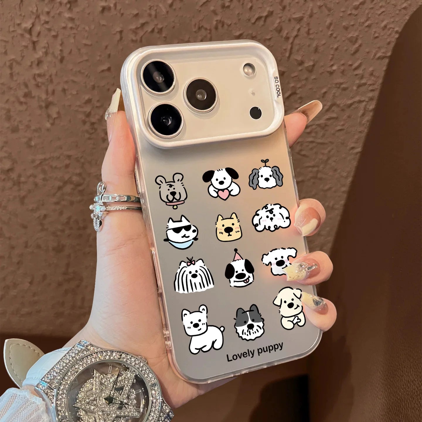 Phone case with cute dog illustrations held by a person against a brown background